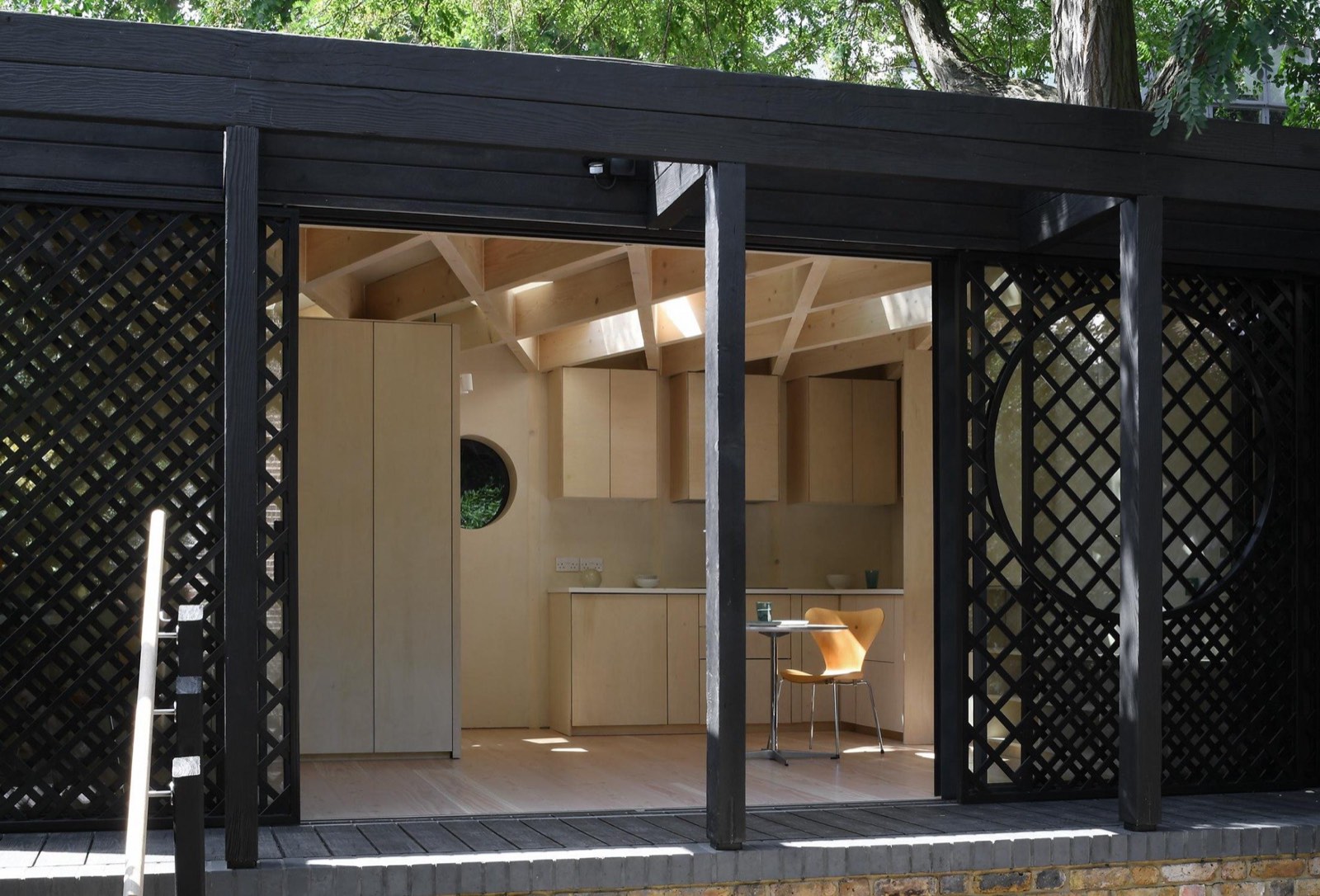 A charred timber garden building with a decorative lattice screen at Stockwell Park Road
