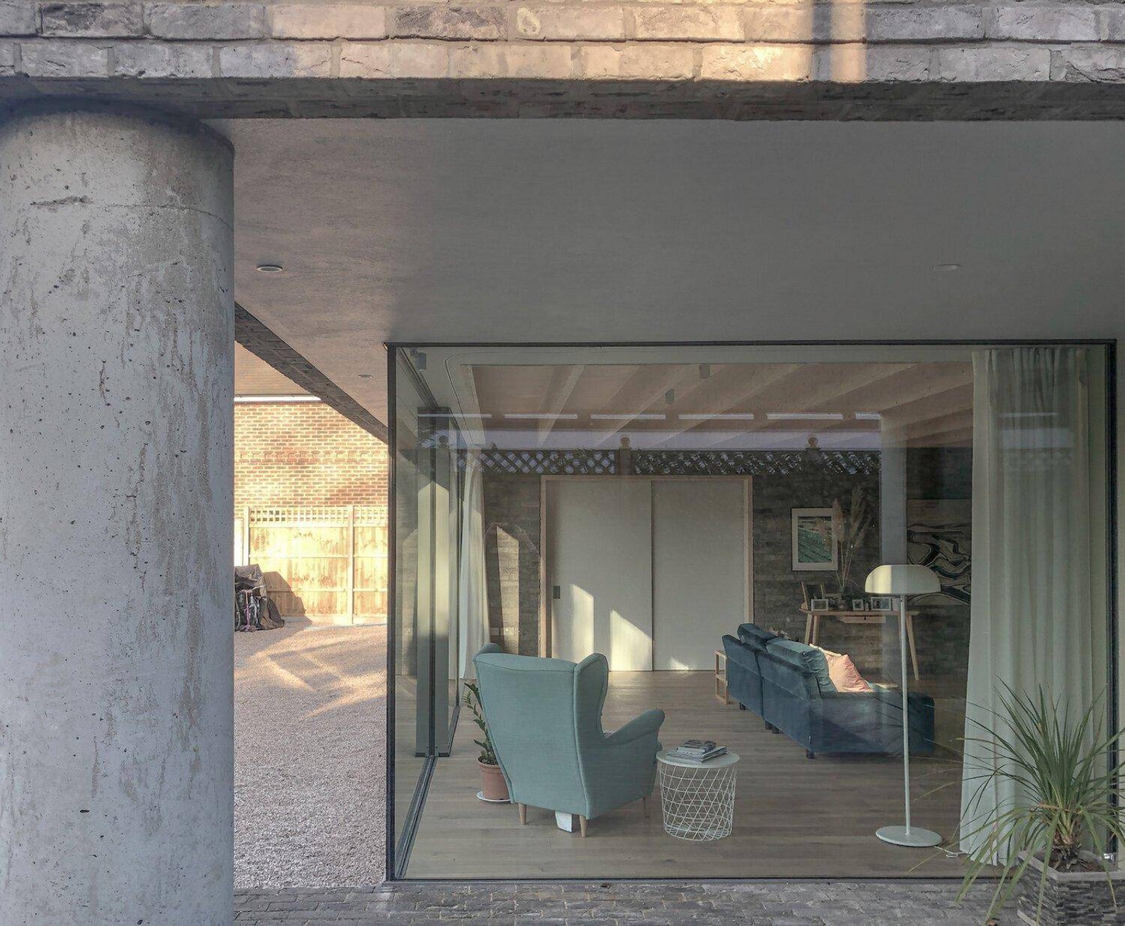 Weybridge House, a board-formed concrete home with full-height glazing opening onto a lawn
